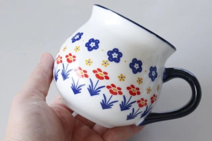 女性の手で持たれたポーリッシュ風の花柄マグカップ