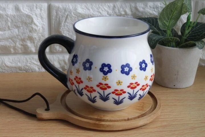 ポーリッシュ風の花柄マグカップが木製コースターに乗っている