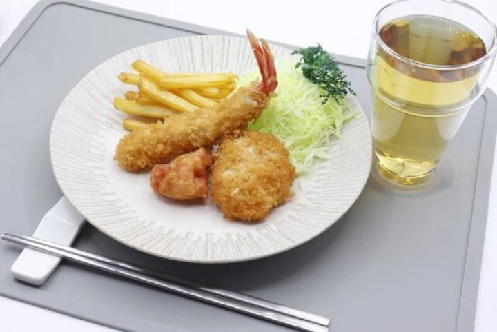 とんかつ皿に揚げ物とフライドポテト、キャベツが盛り付けられた食卓