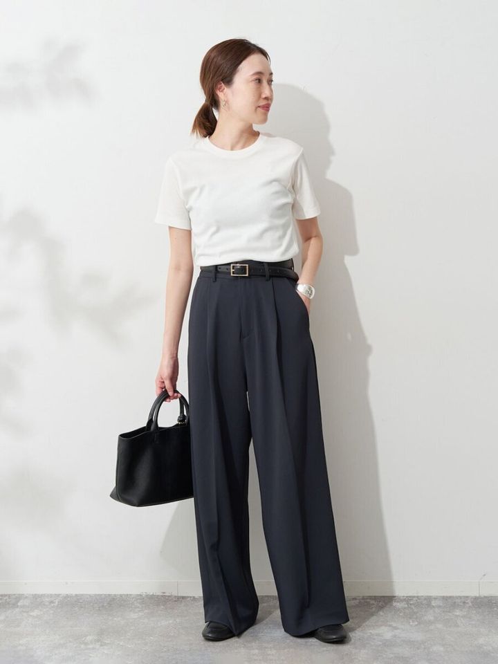 白Tにネイビーのワイドパンツ、黒いバッグを持つ女性