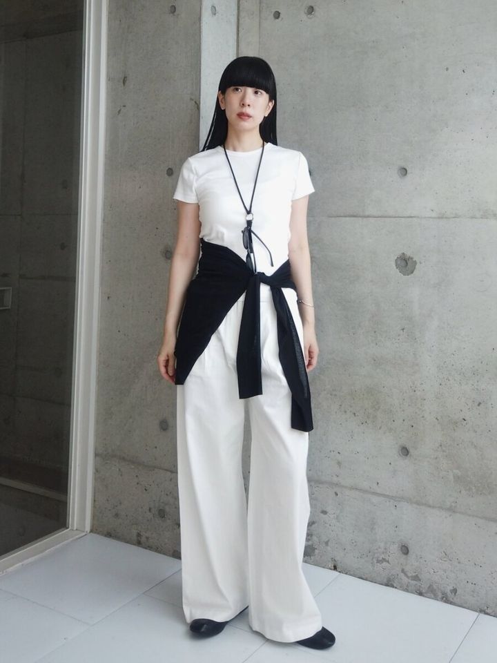 白Tと白いワイドパンツに黒カーディガンを腰巻きした女性