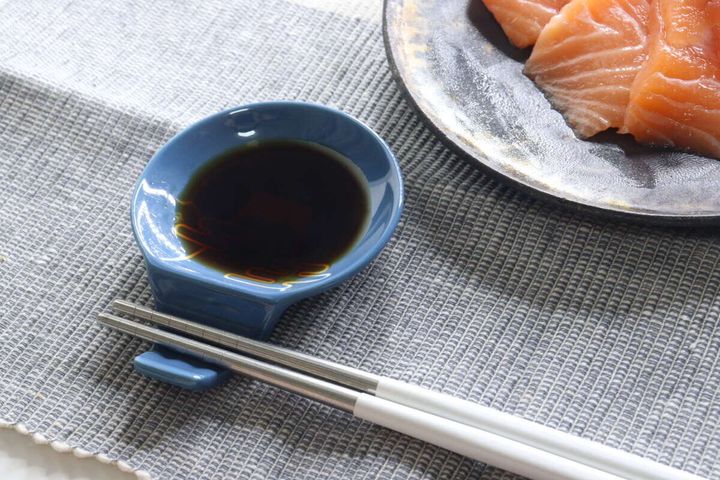 青い箸置き豆皿に醤油が入り、箸が置かれた食卓