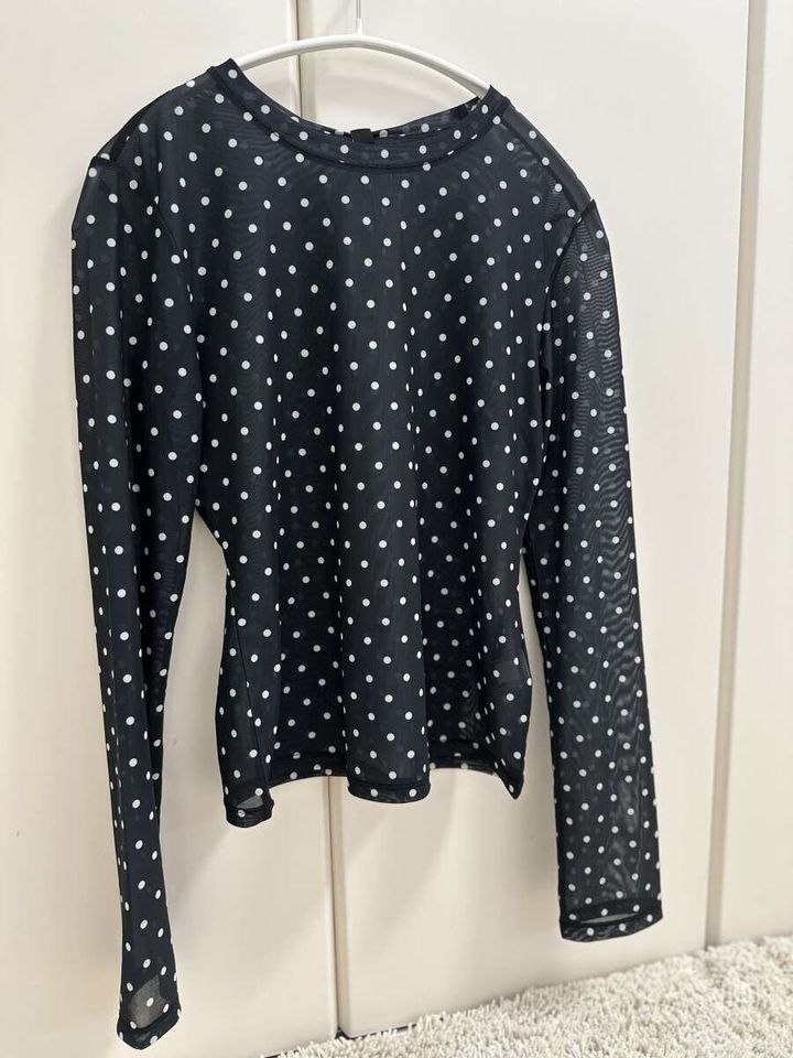 ハンガーにかけられた黒地に白いドット柄のシアーTシャツ