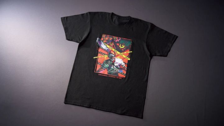 赤いパネルの中でチェンソーの刃を掲げるチェンソーマンをプリントした黒いTシャツ