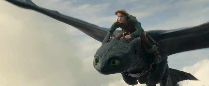 青灰色の空を飛ぶ黒いドラゴンのトゥースと少年ヒック