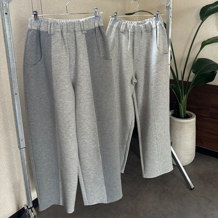 濃淡グレーのカーブシルエットパンツ2本がハンガーに並ぶ