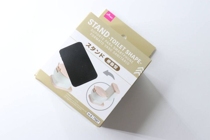 白い背景に斜めに置かれた、ダイソーの便器型スマホスタンドのパッケージ