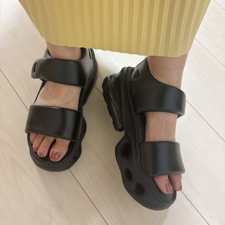 黄色いプリーツスカートを履いた足元に、黒いエアマックスヘイローサンダルを着用している