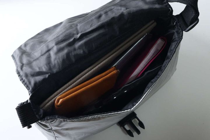 銀色のバッグの中に薄型財布やメモ帳、イヤホンが入っている様子