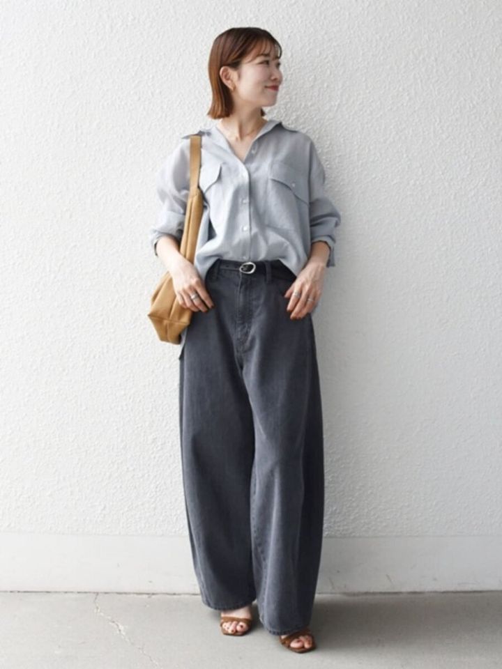 ライトグレーのオーバーシャツとグレーのワイドデニムを着用し、キャメルバッグを持つ女性