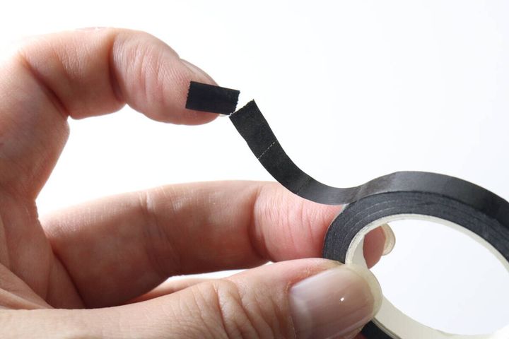 指でミシン目に沿ってマスキングテープをちぎる様子