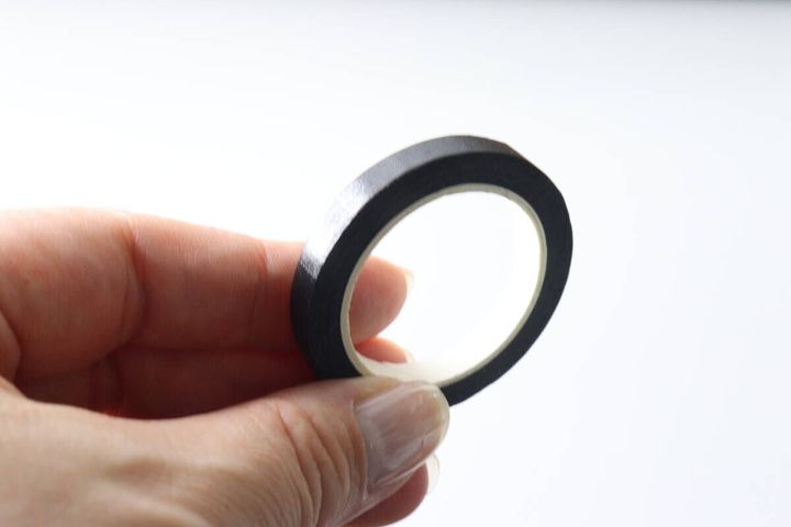 指で持たれた黒い暗記用マスキングテープのロール