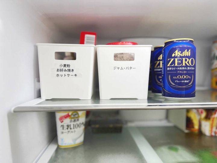 冷蔵庫の棚にラベル付き収納ケースと缶ビール
