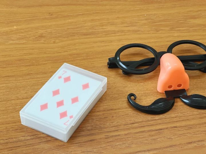 木目のテーブルにトランプと鼻メガネの変装グッズ