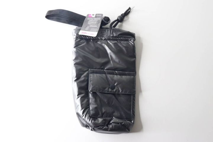 白い背景に置かれた黒いボトルホルダー。商品タグが付いている。