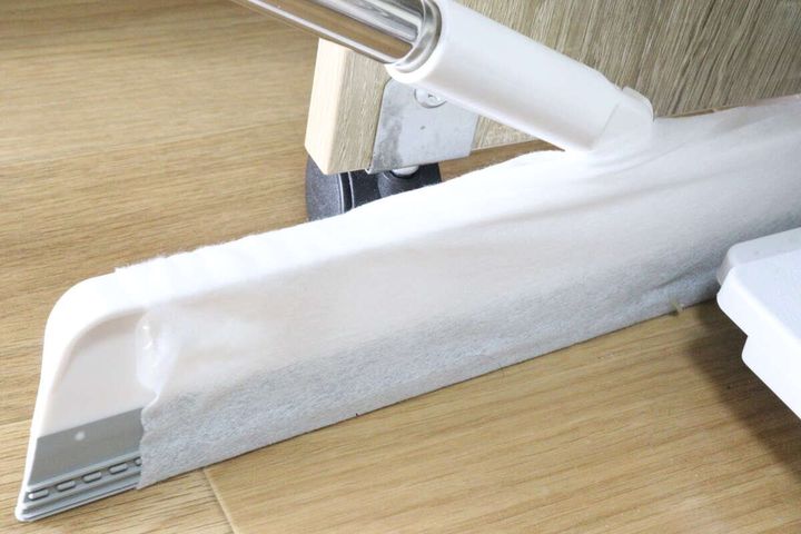 掃除シートを付けたワイパーで家具の隙間を掃除している様子