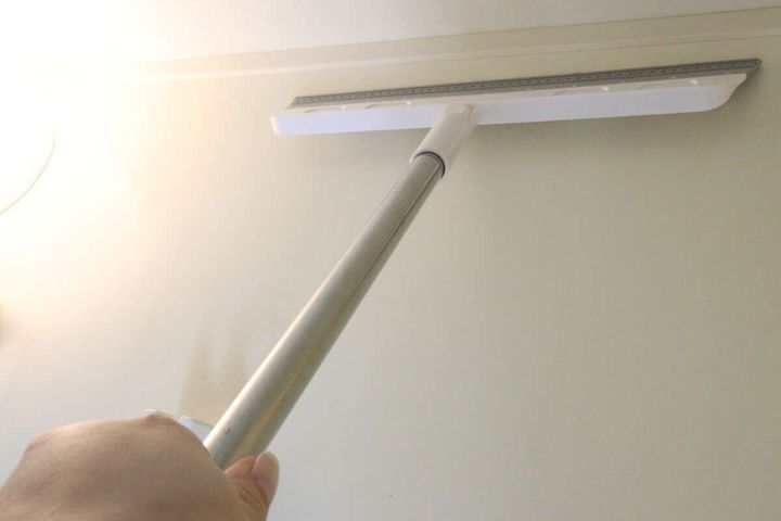 白いワイパーで壁の水滴を拭き取っている様子