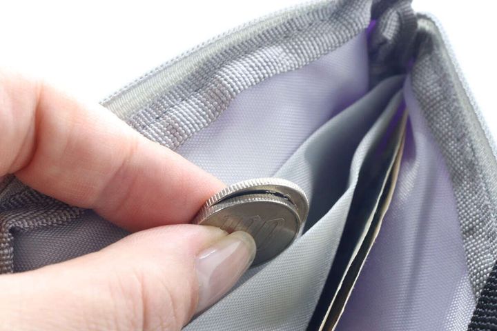 女性の指がダイソーコインケースに小銭を入れている