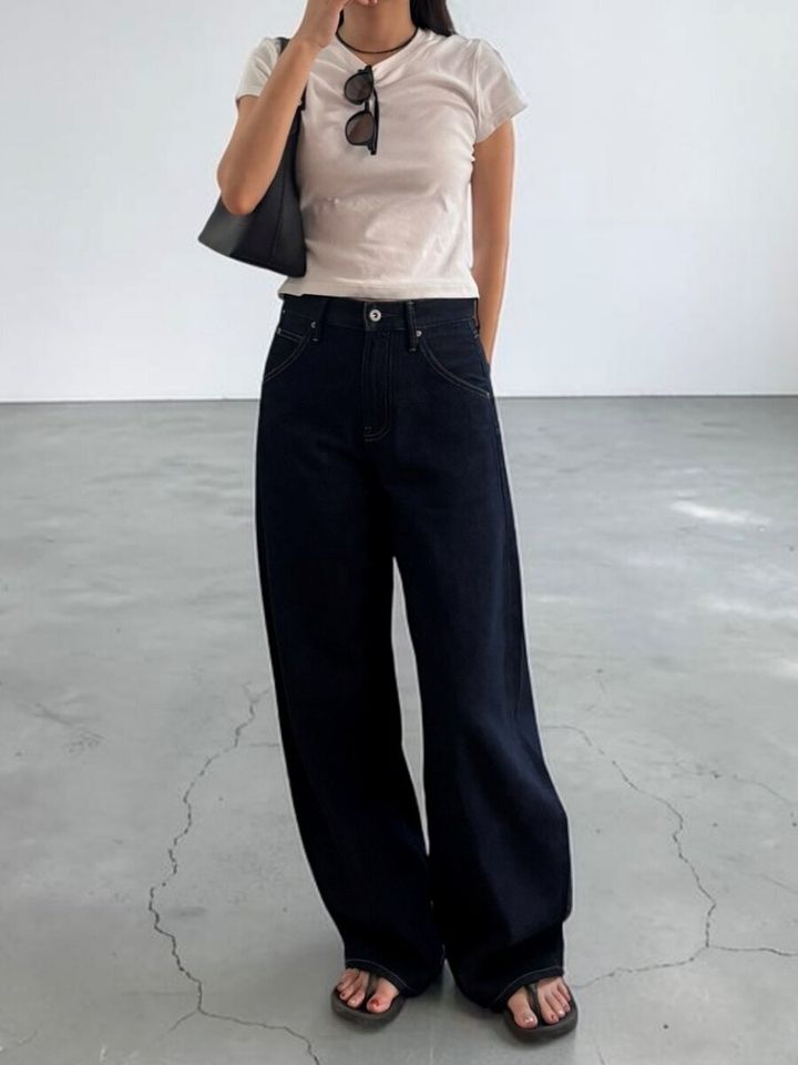 白いミニTシャツと黒いジーンズを合わせた女性