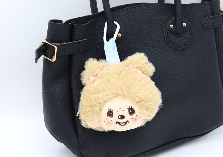 黒いバッグにモンチッチチャームが取り付けられている