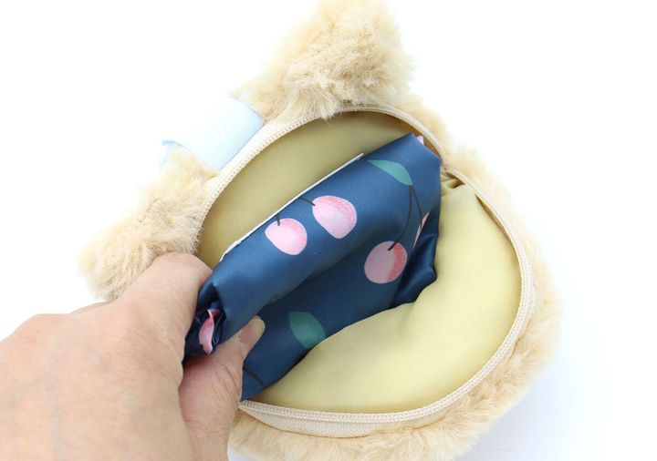 モンチッチチャームにエコバッグを収納している手元