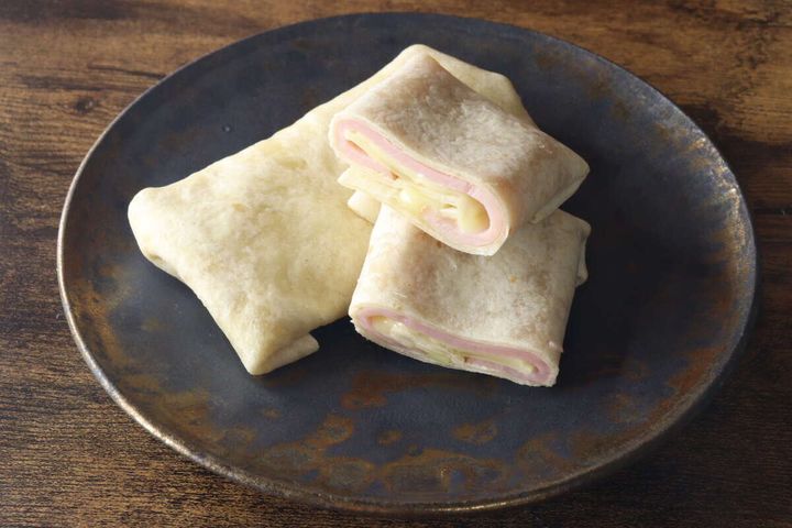 黒い皿に盛り付けられた、ハムとチーズのトルティーヤが半分にカットされている