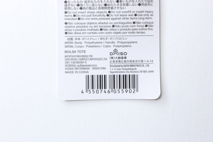 ダイソーのトートバッグのタグ。JANコードや素材、使用上の注意書きが記載されている