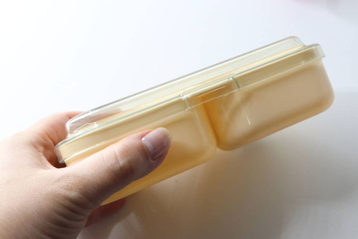 女性の手がダイソーおにぎりランチBOXの側面を持つ