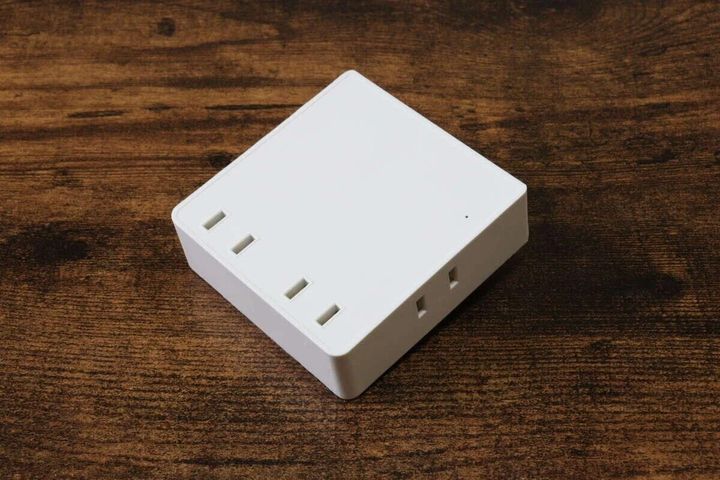 白い四角い4個口スクエアタップが、木目調のテーブルの上に置かれている