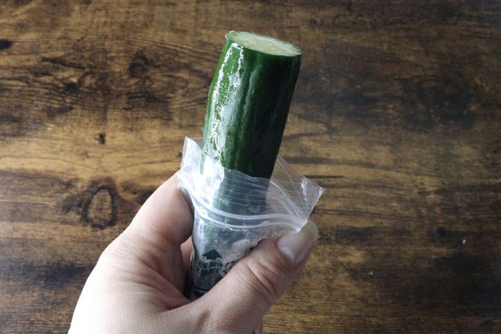 女性の手が一本漬け袋からきゅうりを取り出して持つ
