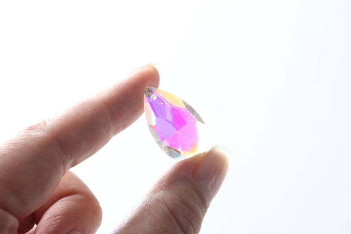 指で大きな虹色のビーズをつまんで光にかざしている様子