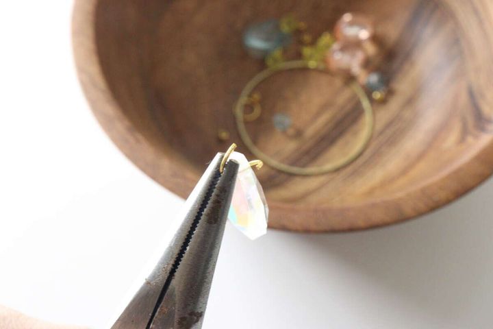 ペンチを使って丸カンを開いている手元のアップ
