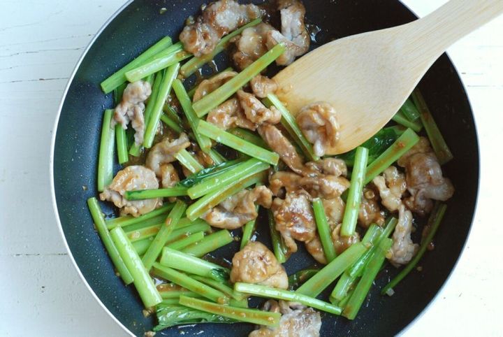 フライパンで豚こま切れ肉と小松菜の茎に味噌ベースのタレが絡められている様子