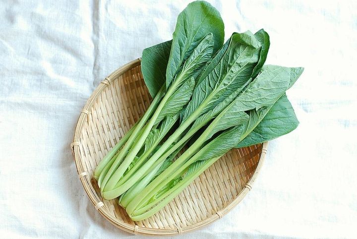 竹製のざるに盛られた新鮮な緑色の小松菜の束