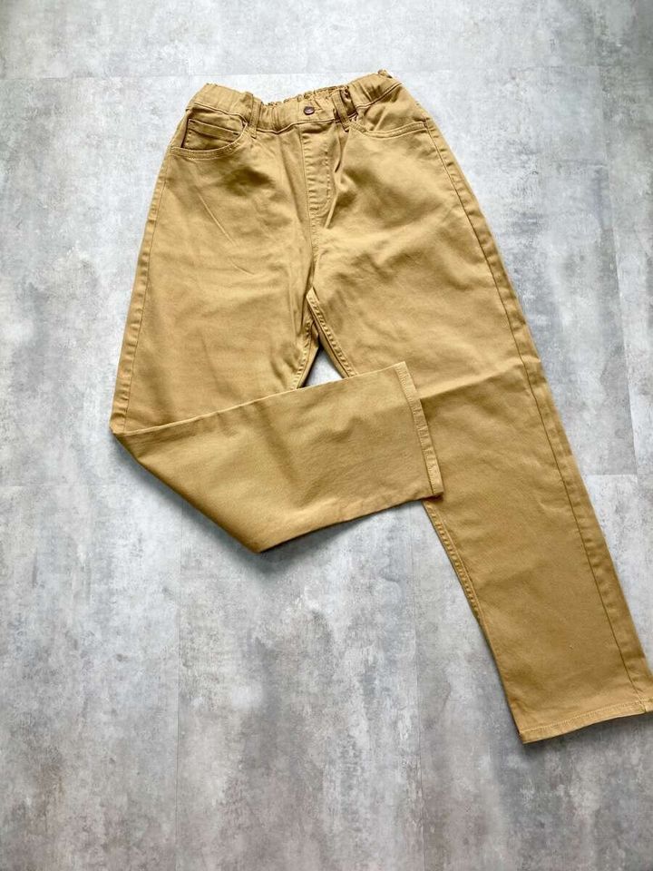 ベージュのKIDSストレッチストレートパンツSTを広げて床に置いた状態
