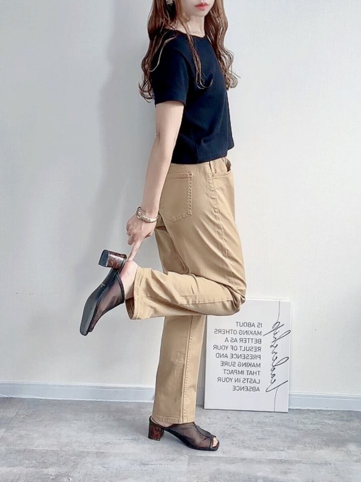 黒いTシャツとベージュのKIDSストレッチストレートパンツSTを着用し、足元を見せる女性の横向き姿