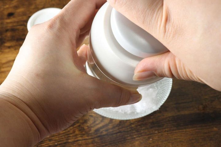 両手でかき氷機を操作し、氷を削って器に入れている様子