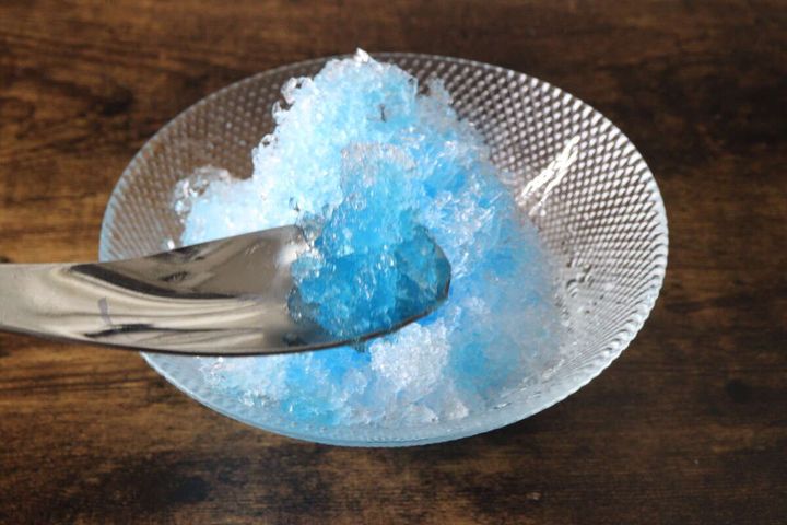 ブルーハワイのかき氷を銀色のスプーンですくっている様子
