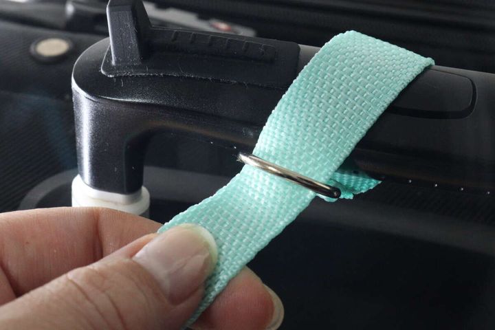 女性の手がスーツケースのハンドルにリードの金具を通している