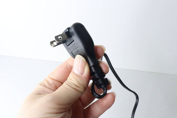 女性の手が角度調整可能なスイング式電源プラグを持っている