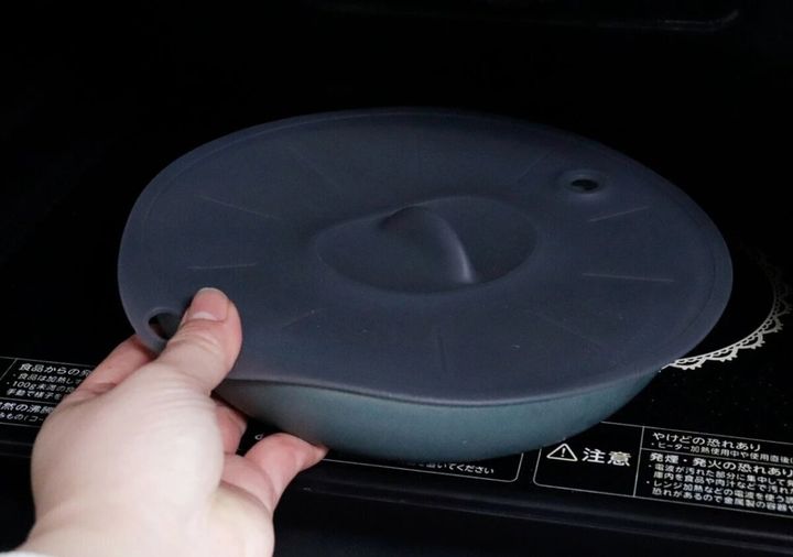 シリコーン蓋をかぶせた皿を電子レンジに入れる手