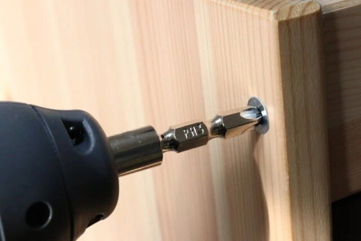 電動ドライバーで木製家具のネジを締めている様子