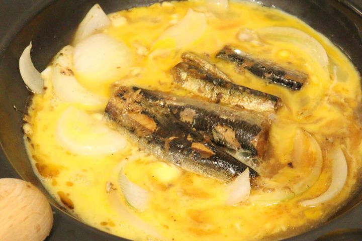 いわしと玉ねぎを煮込んだフライパンに溶き卵を投入