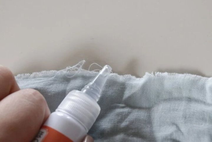 布のほつれた部分にほつれ止め液の先端を当てて塗っている手元