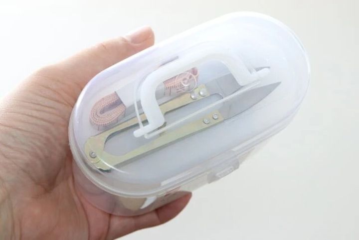 透明なケースに入ったソーイングセットを片手で持っている