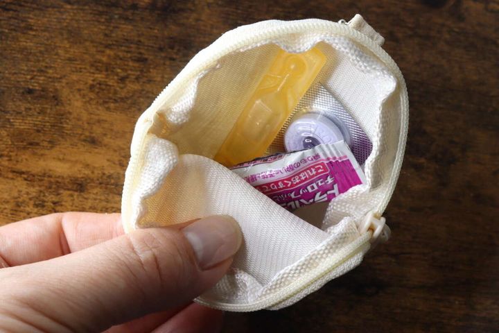 開いた白いキーホルダーポーチの中に常備薬やトローチが入っている様子