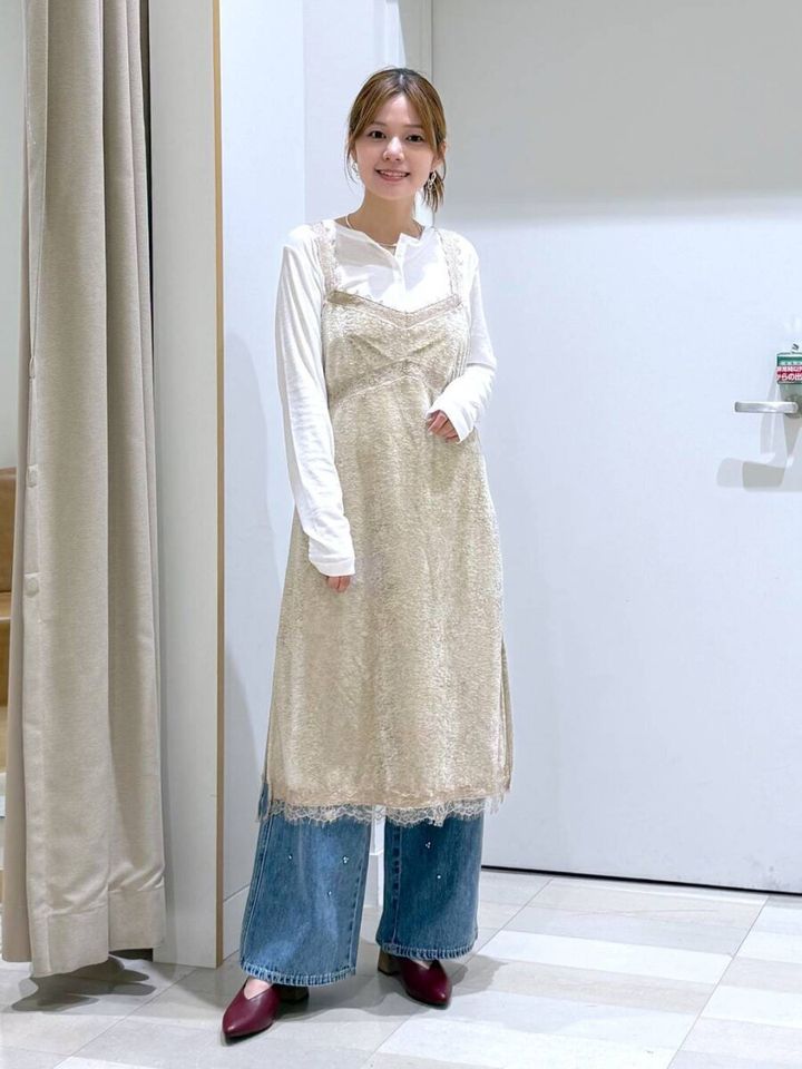 白い長袖Tシャツにベージュのベロアレースワンピの女性