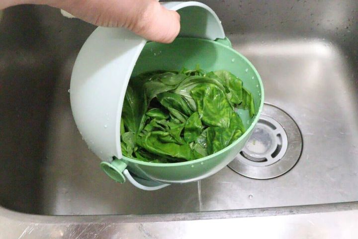 水切りザルボウルで緑の葉物野菜を水切りしている