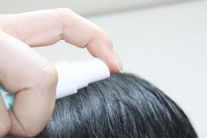 黒髪の頭皮にドライシャンプーをスプレーしている様子