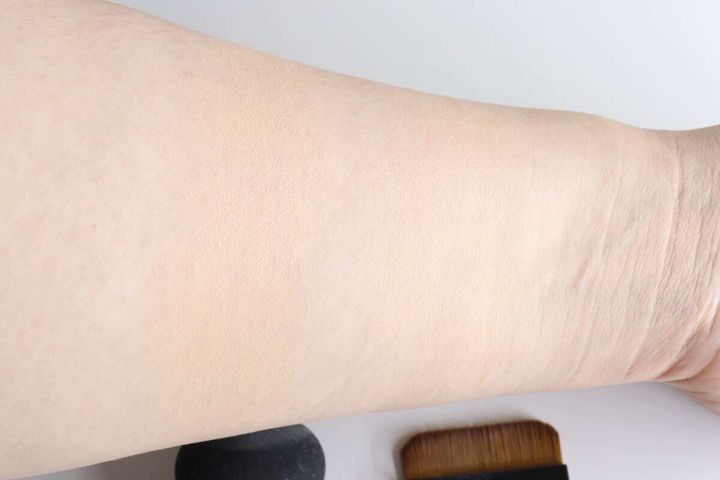 ファンデーションを塗布した腕とブラシ、スポンジ